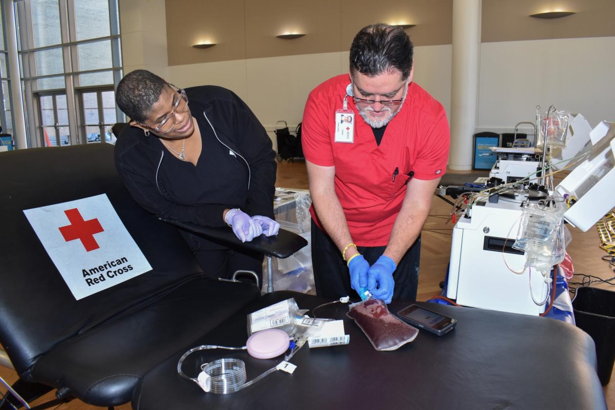 Two Red Cross employees inspect a blood bag during the blood drive hosted by GW Red Cross in the University Student Center Grand Ballroom.