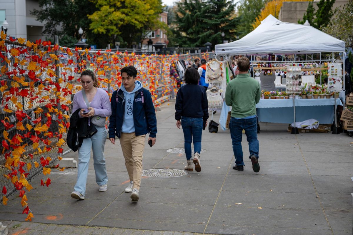 Pedestrians walk between fences and farmers market tents on the I Street Mall.