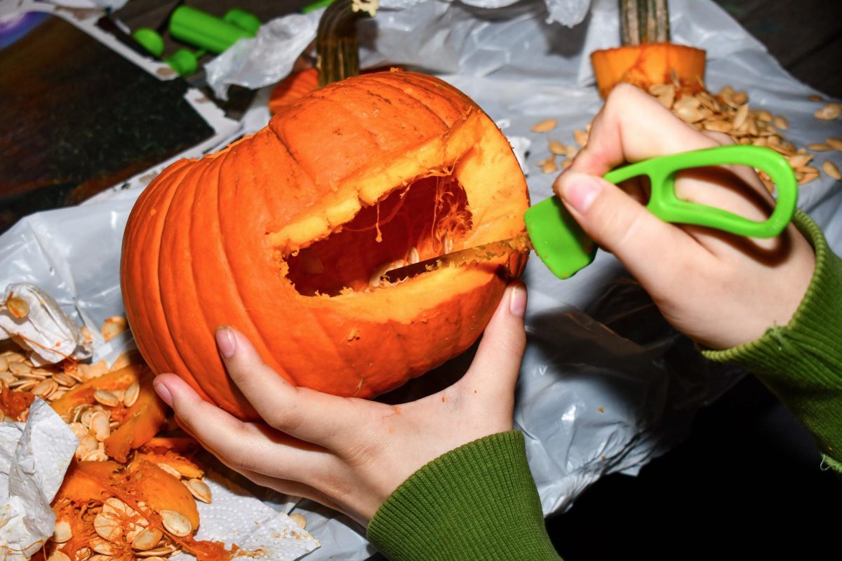 A student carving jack-o'-lanterns in Kogan Plaza