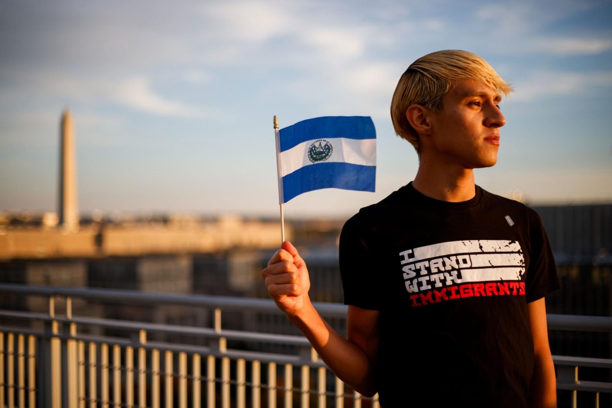 Senior Javier Orellana poses with the El Salvadoran flag on the roof of 1959 E Street.