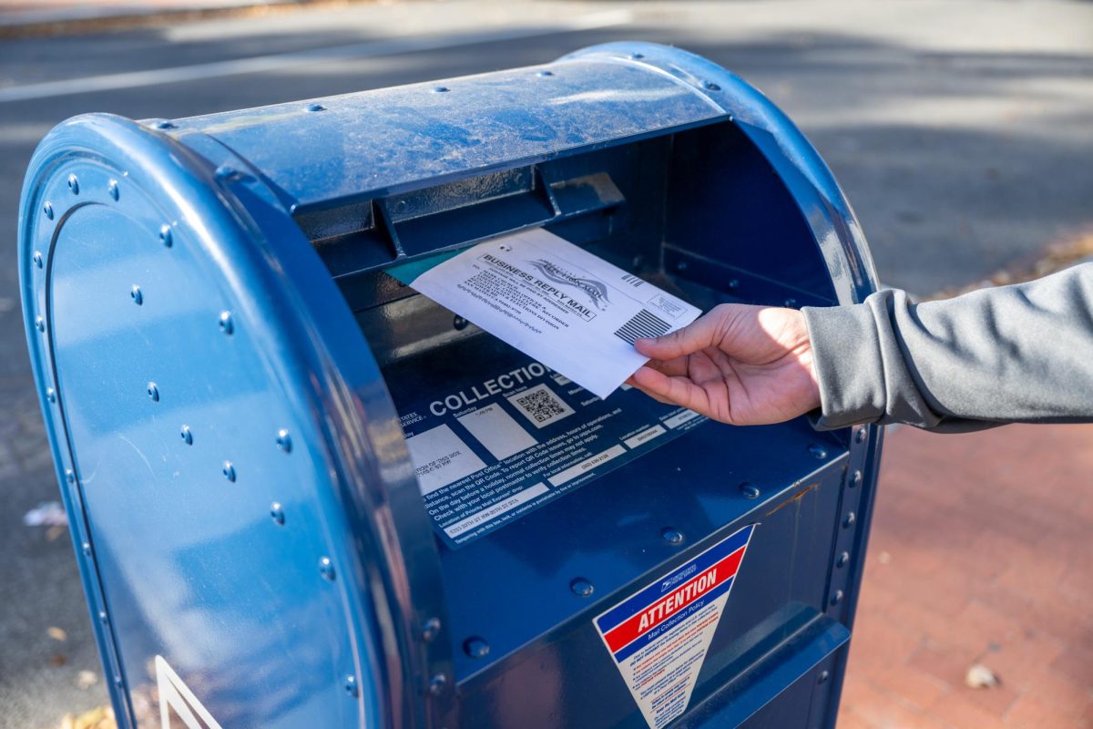 A student drops their absentee ballot into a on-campus mail box.