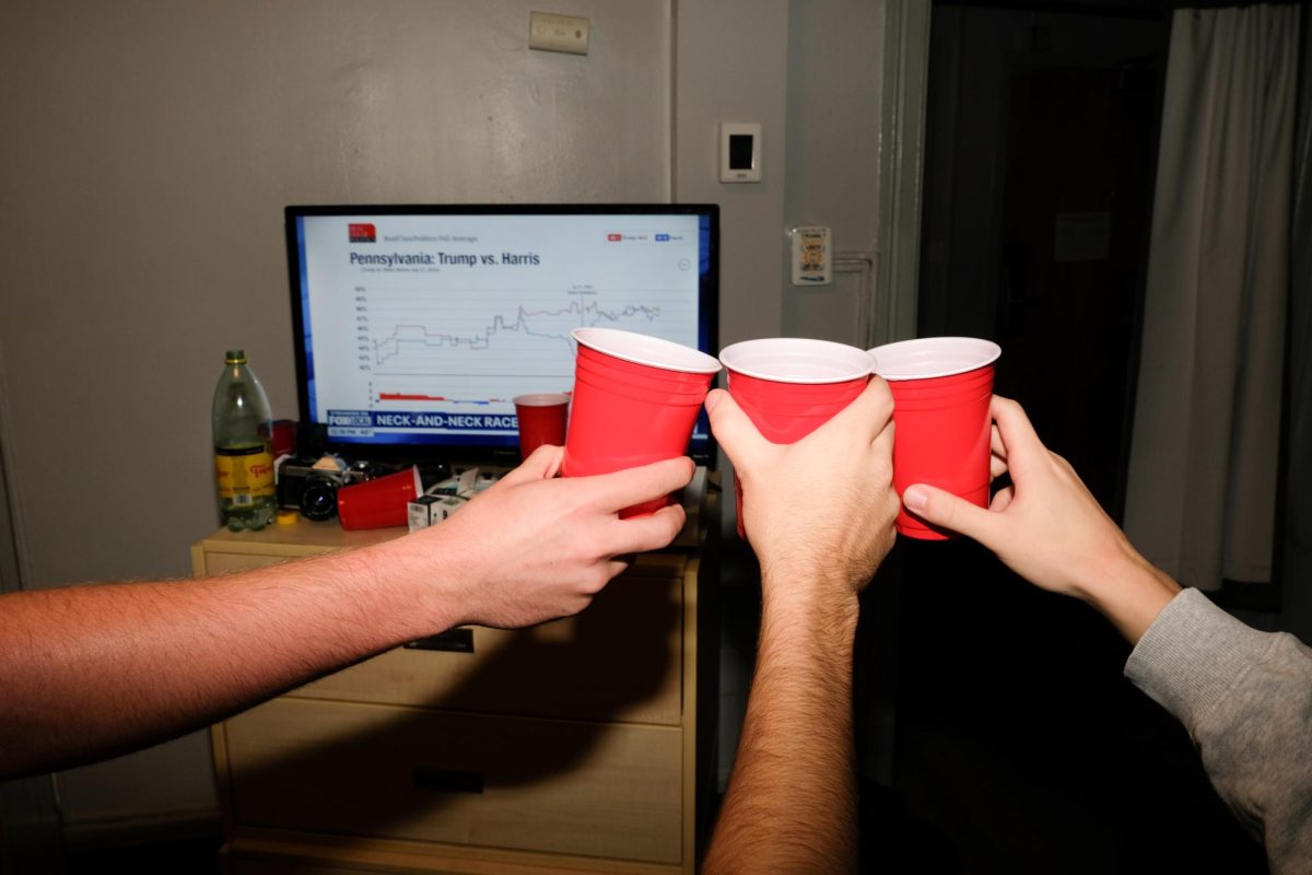 Three friends play a drinking game as poll results come in.