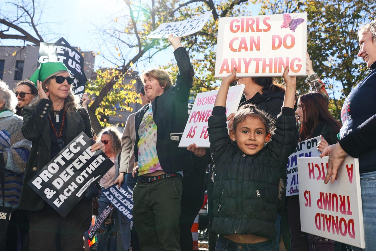 A girl raises a sign at the 2024 Women's March in front of the Heritage Foundation headquarters.