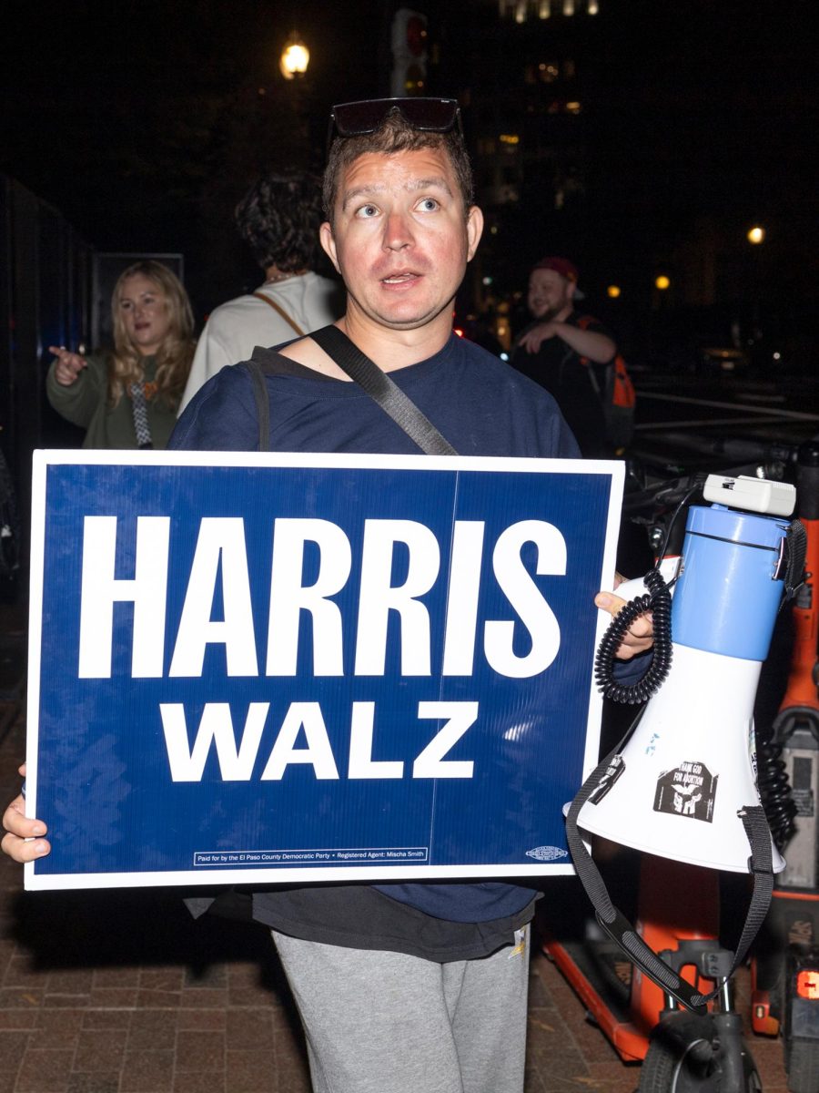 Derek Torstenson stands with a pro-Harris sign and megaphone outside of the White House gates.