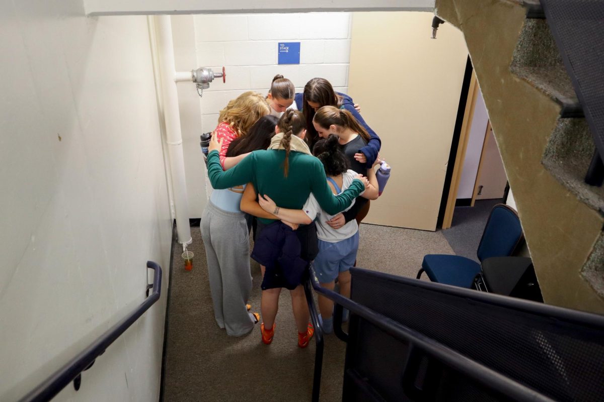 Student choreographer Livvy Loxton takes a moment with her dancers for one last hug before the start of rehearsal.