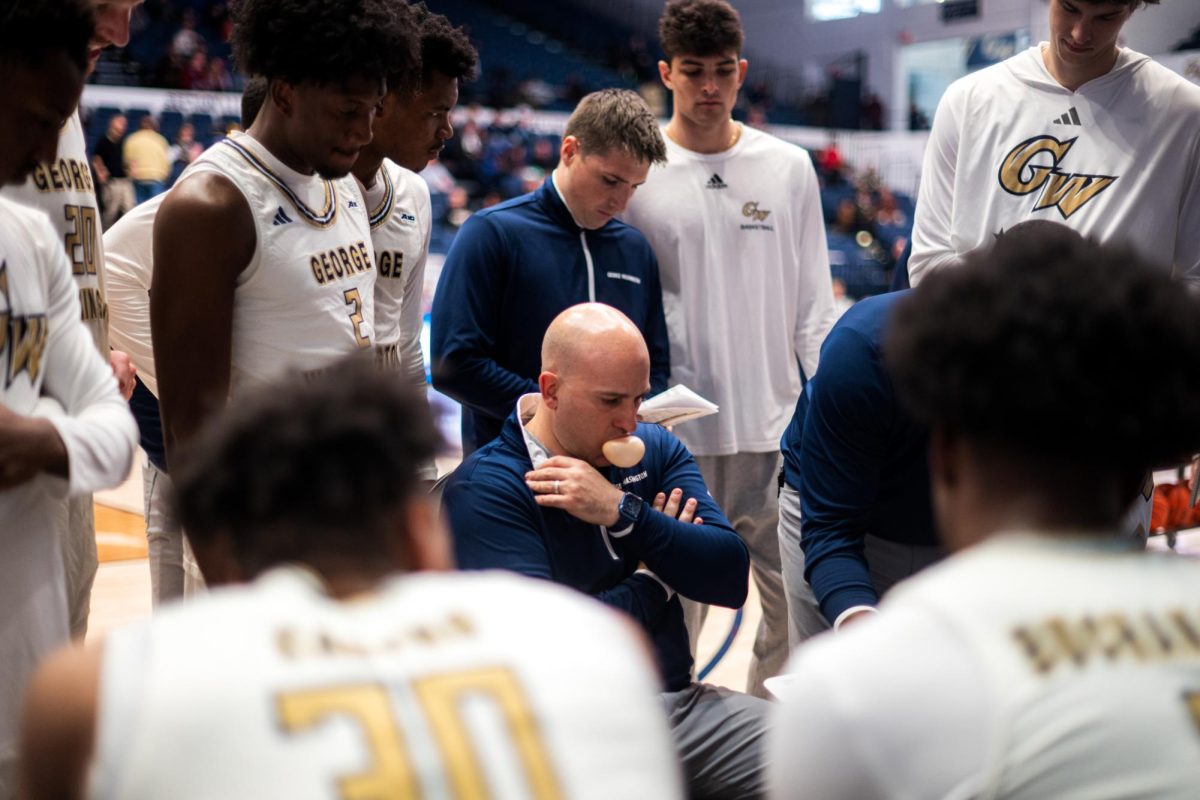 The men's basketball team circles around Head Coach Chris Caputo during a timeout this week in a game against Virginia Military Institute. 