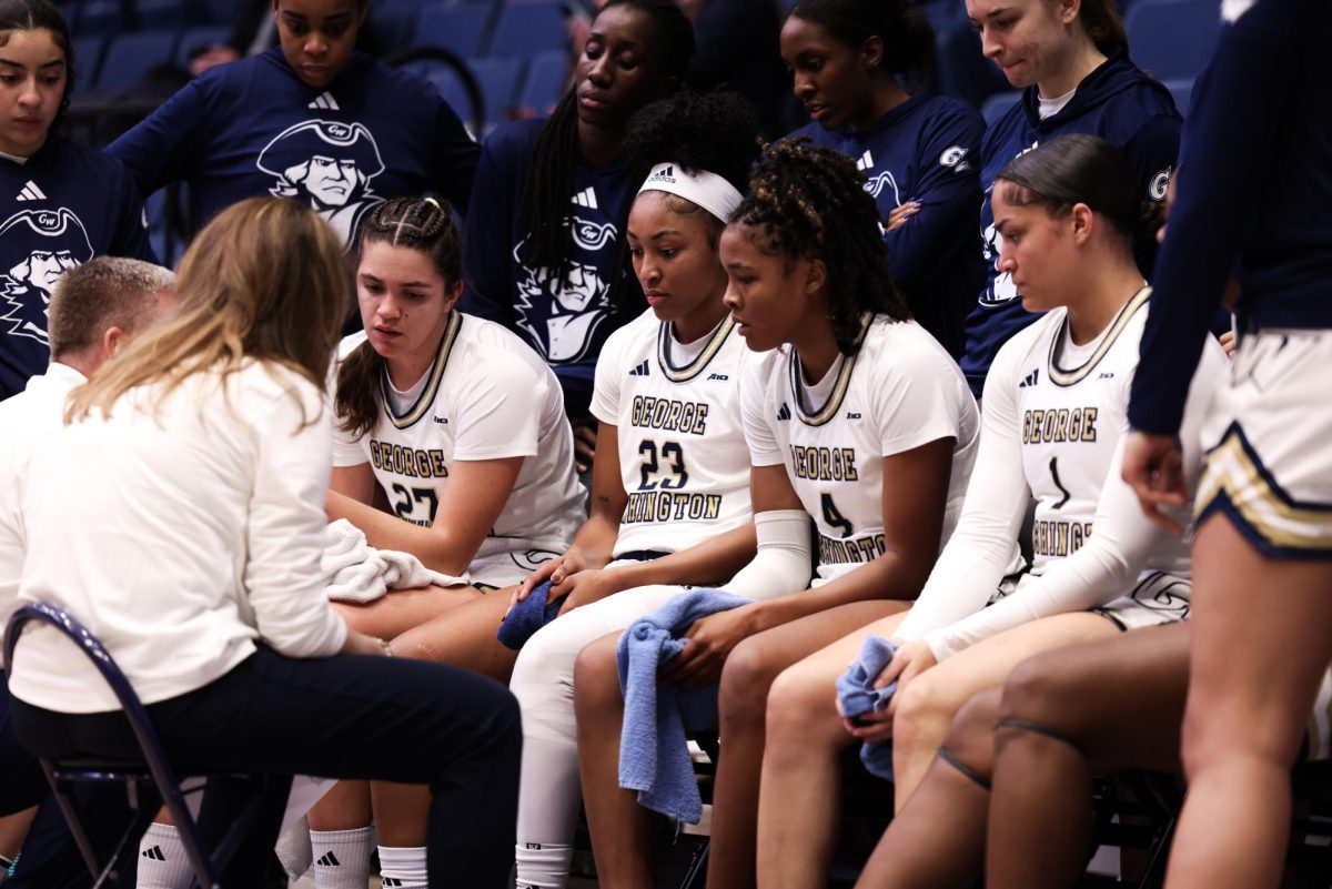 Graduate guard Makayla Andrews, sophomore forward Sara Lewis, and freshman guard Gabby Reynolds sit in a time out led by head Coach Caroline McCombs.