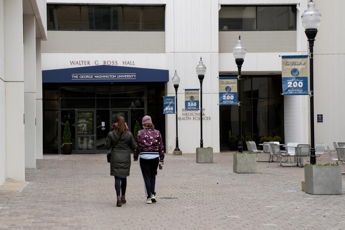 A pair of students hold hands as they walk toward the entrance of Ross Hall.