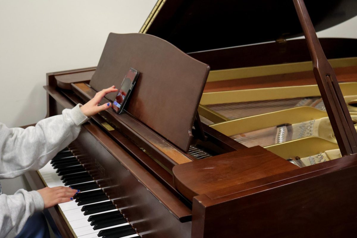 A student plays piano inside of a practice room in the basement of Phillips Hall.