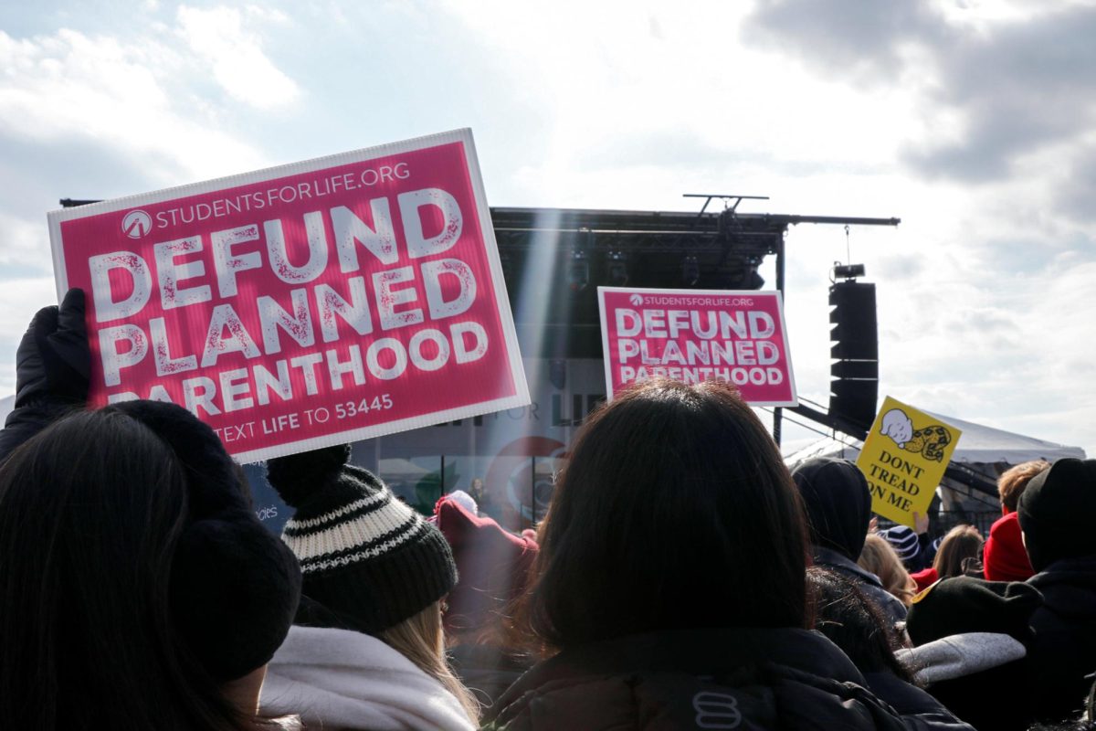 Protesters at the March for Life hold signs in support of defunding Planned Parenthood. 