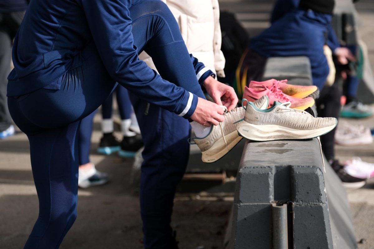 A GW runner ties their shoes before a track practice on Thursday.