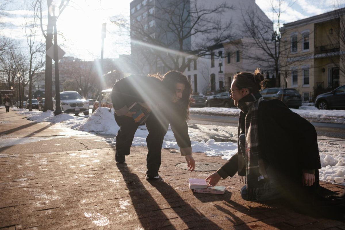 Two students meet over dropped books on the sidewalk of New Hampshire Avenue.