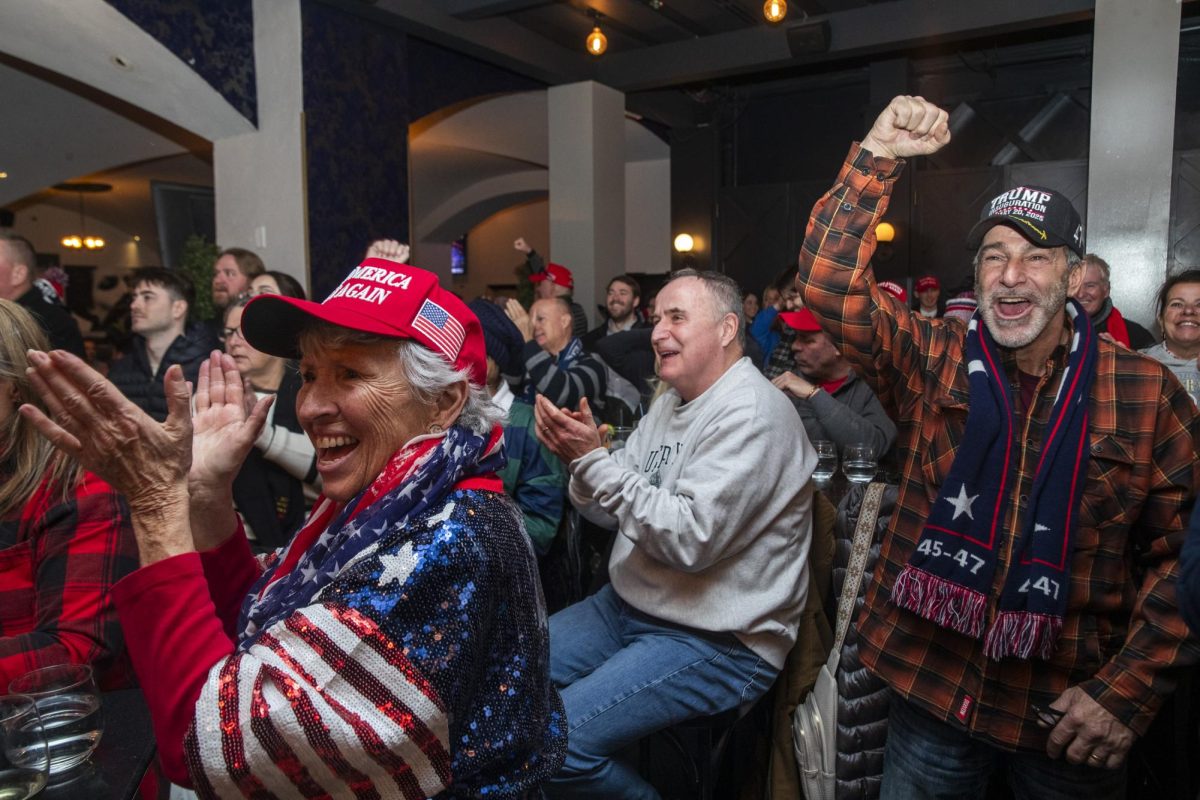 Donning red, white, and blue Trump regalia, supporters cheer from a bar as he is sworn in as president.