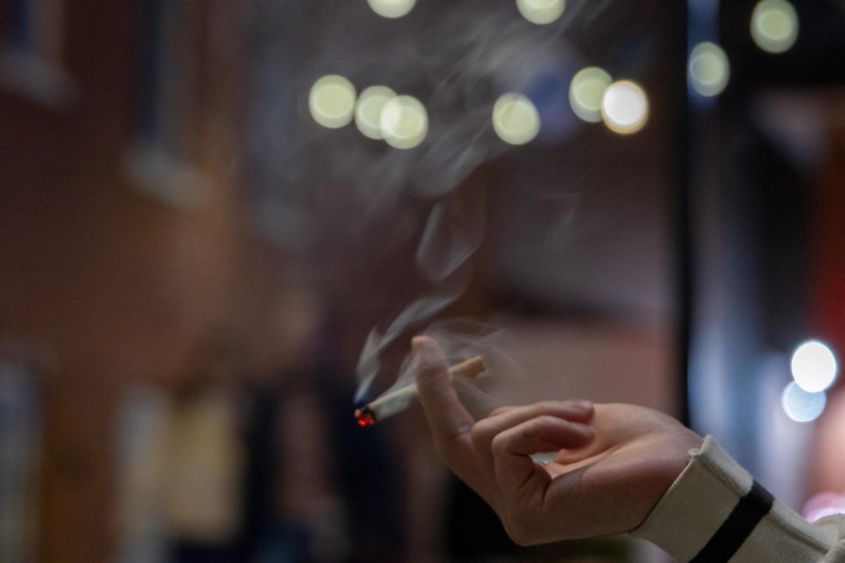 A student smokes a cigarette in Square 80.