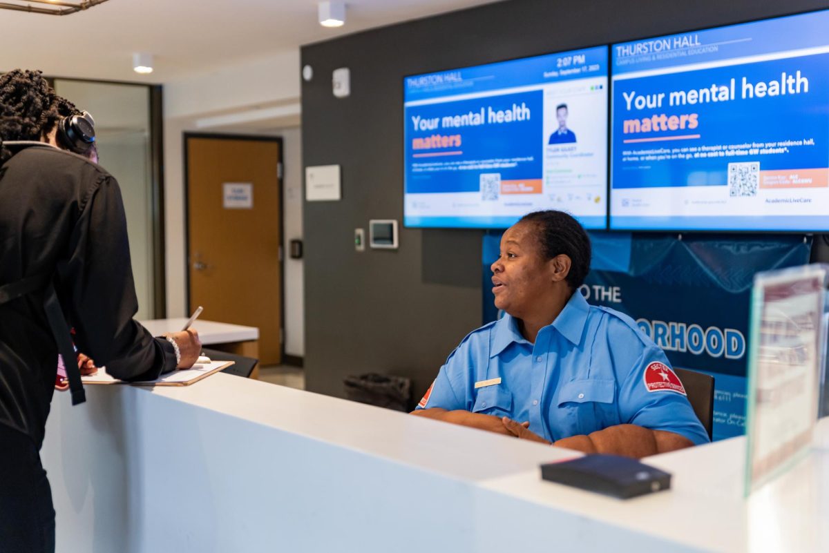 A security guard chats with a student signing in at a front desk in 2023.
