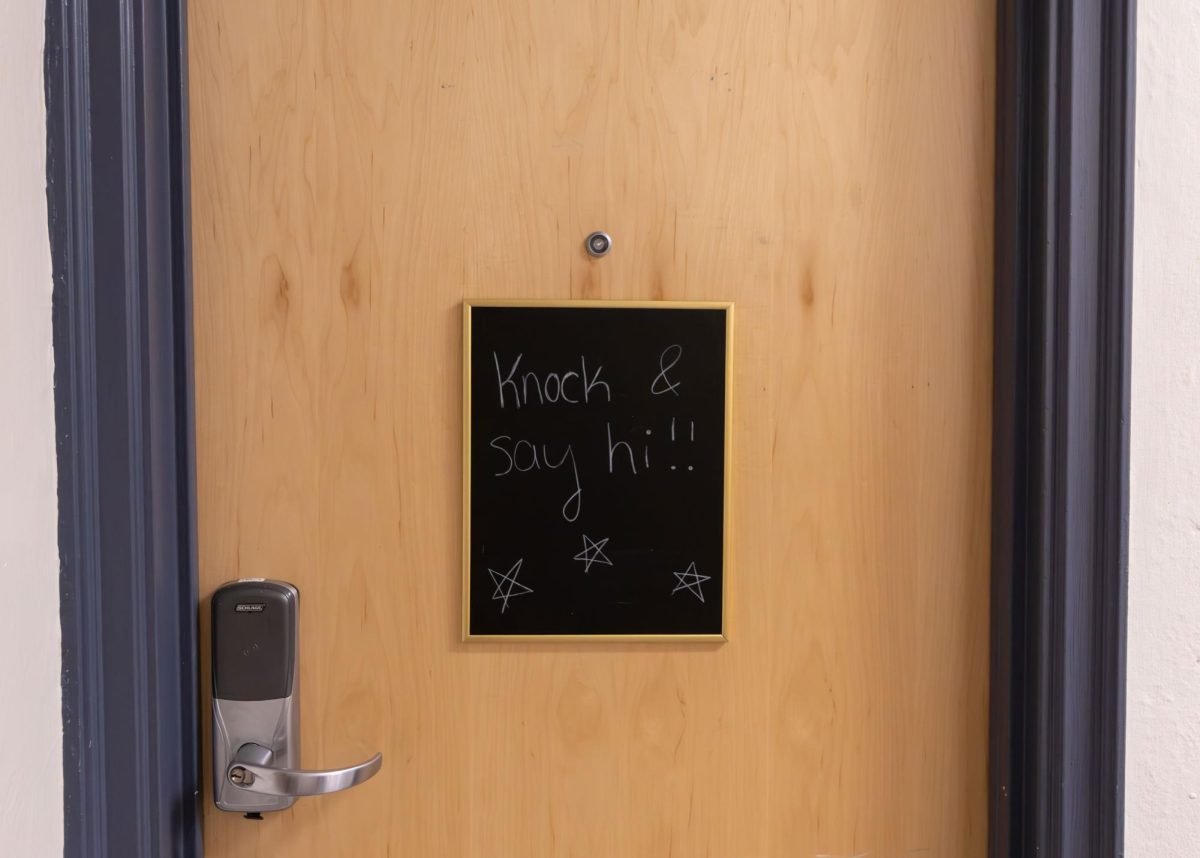 A sign reading "Knock and say hi," on a residence hall door.