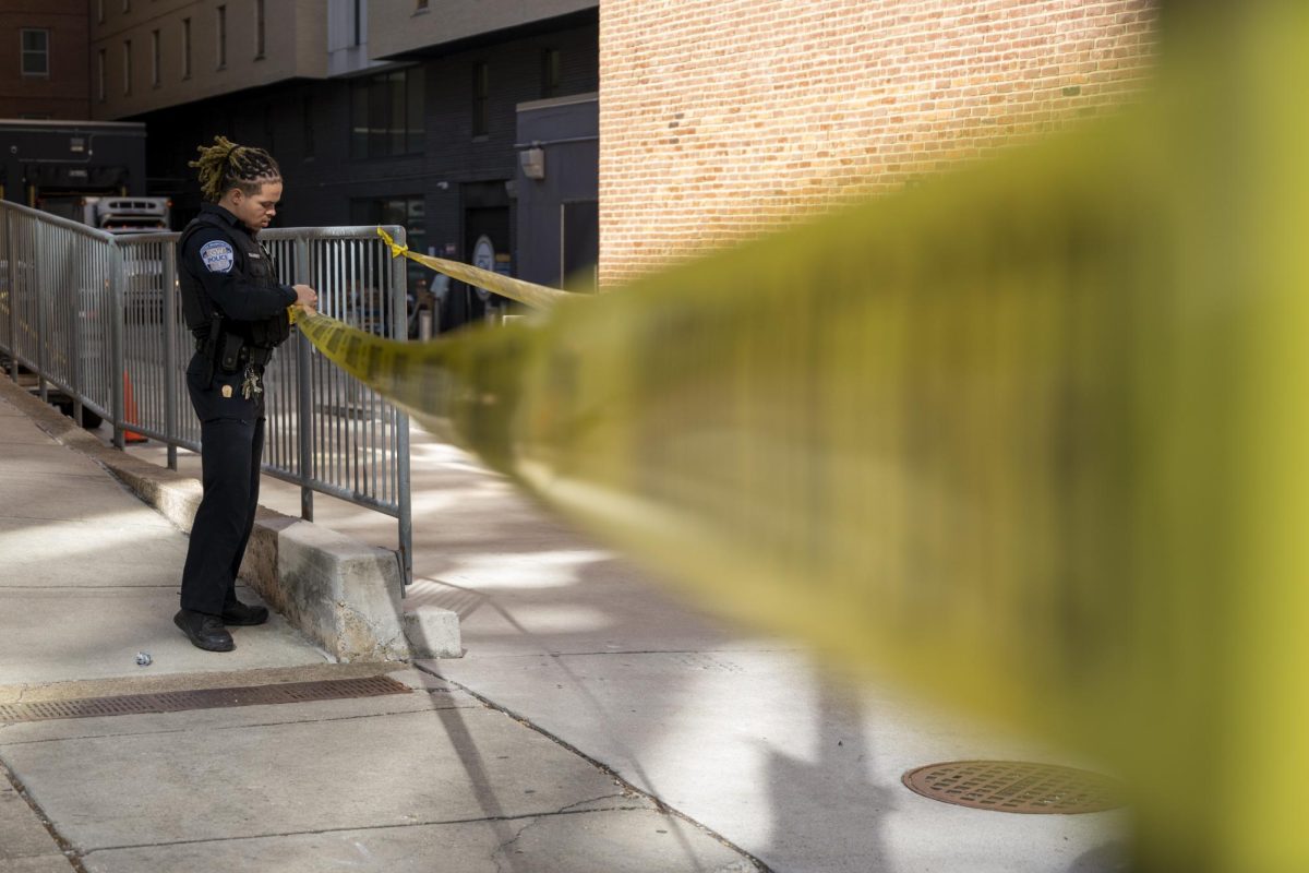 A George Washington Police officer putting up caution tape on I St.