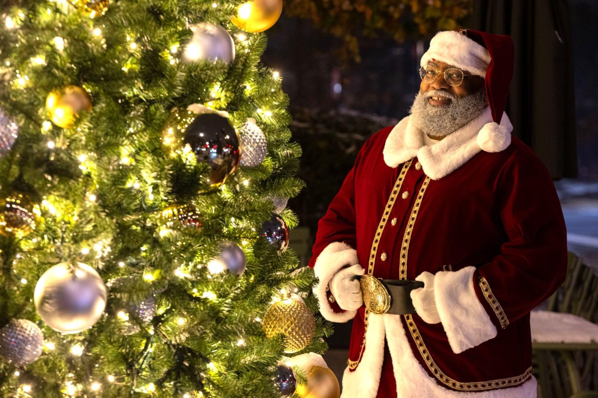 Santa Jeff poses for a portrait by a Christmas tree in Dupont Circle.