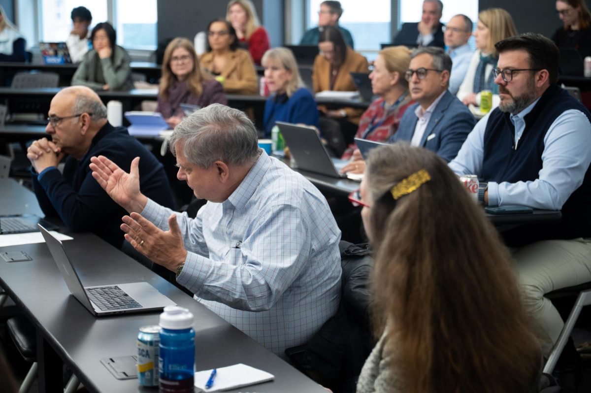 Faculty senator Phil Wirtz raises his hands at Friday's Faculty Senate meeting.