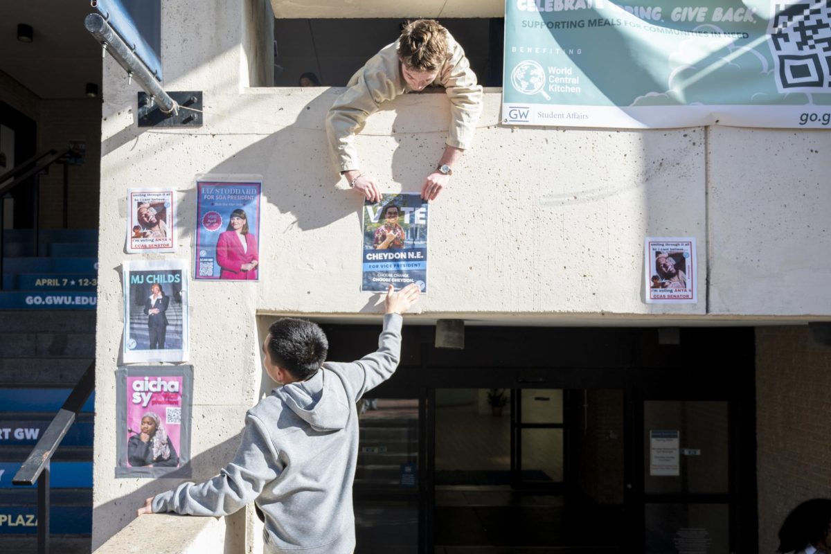Student Government Association Sen. Cheydon Naleimaile-Evangelista (CCAS-U) puts up a poster on the University Student Center on Monday.