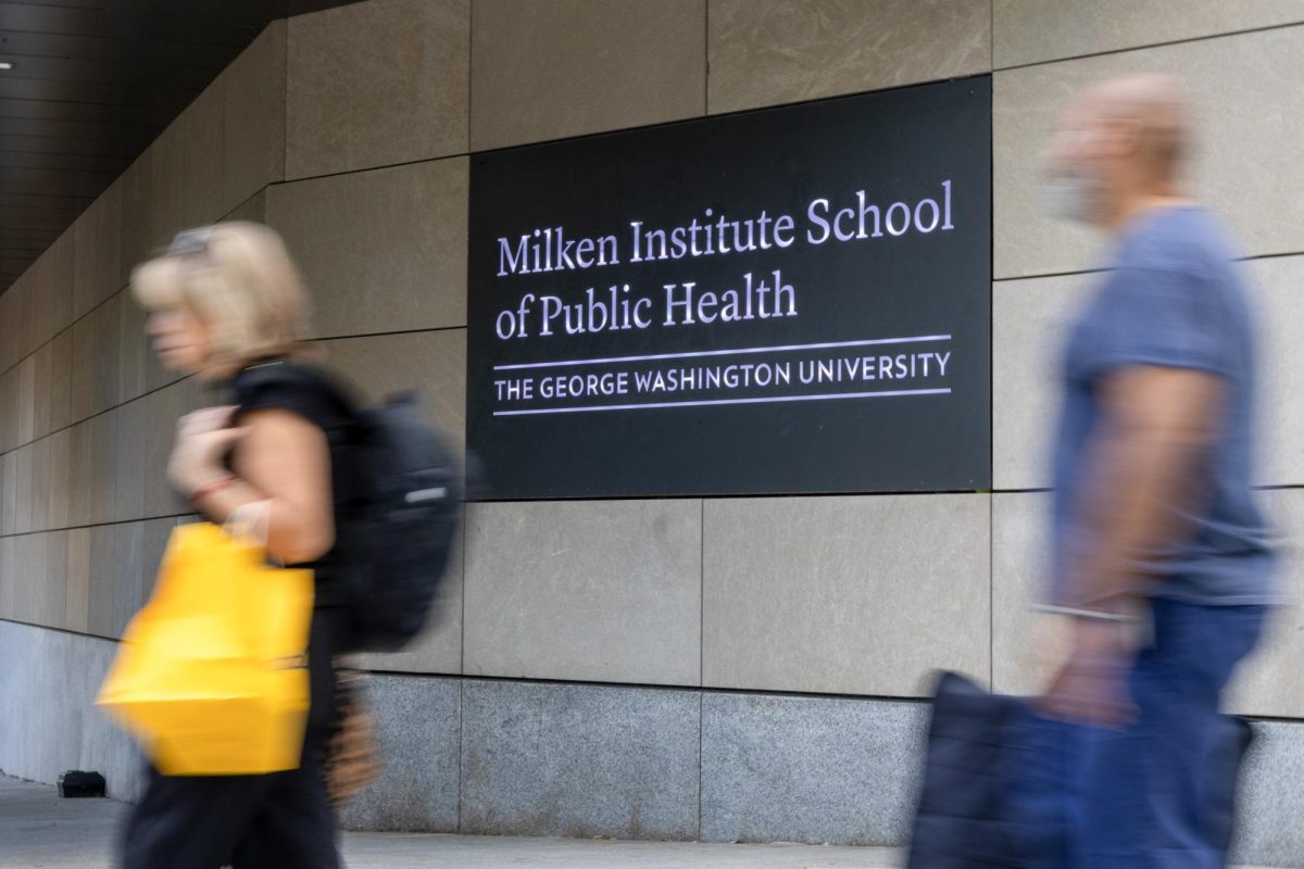 Pedestrians walk past the Milken Institute School of Public Health.