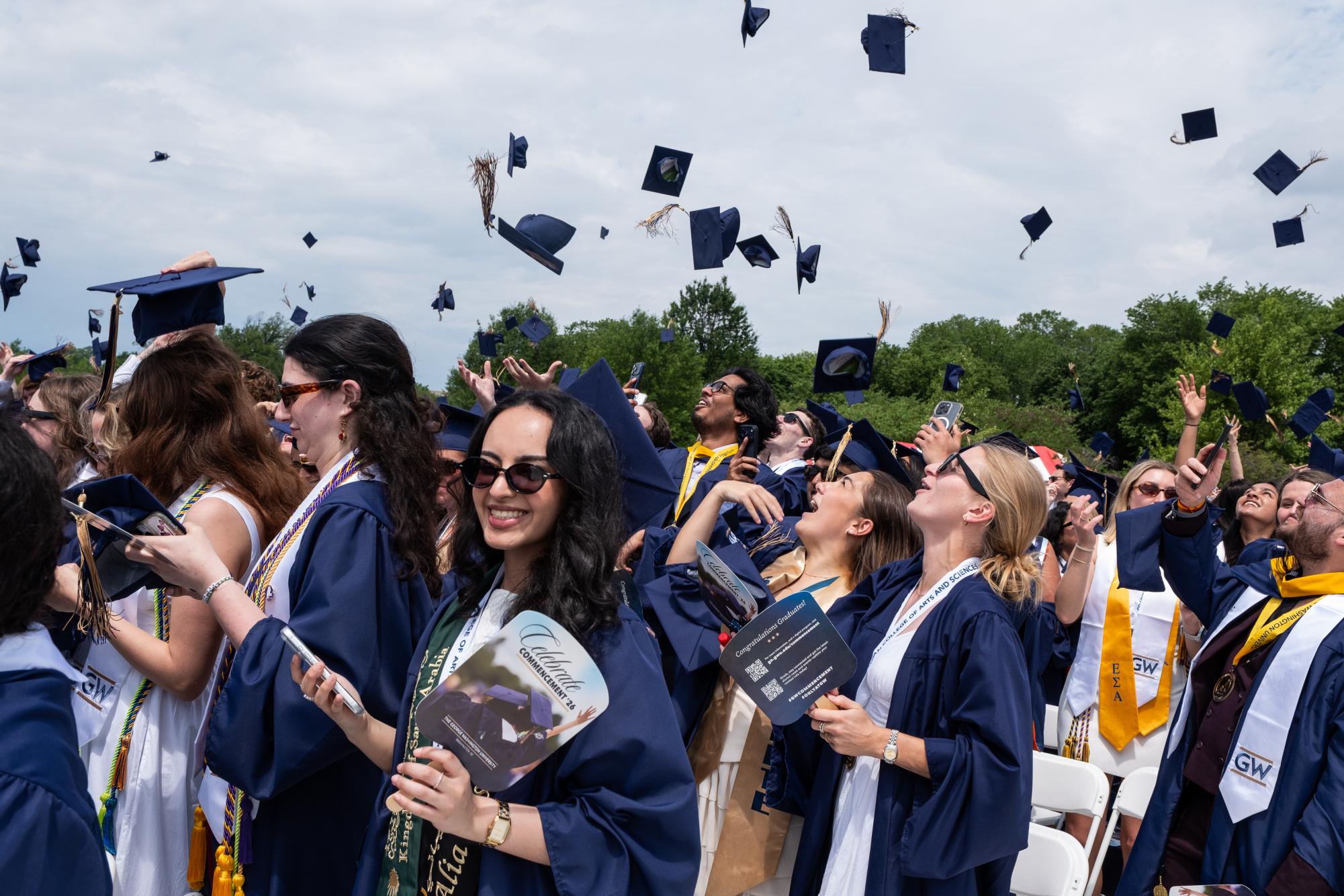 Graduates toss their caps in celebration at University Commencement Sunday.