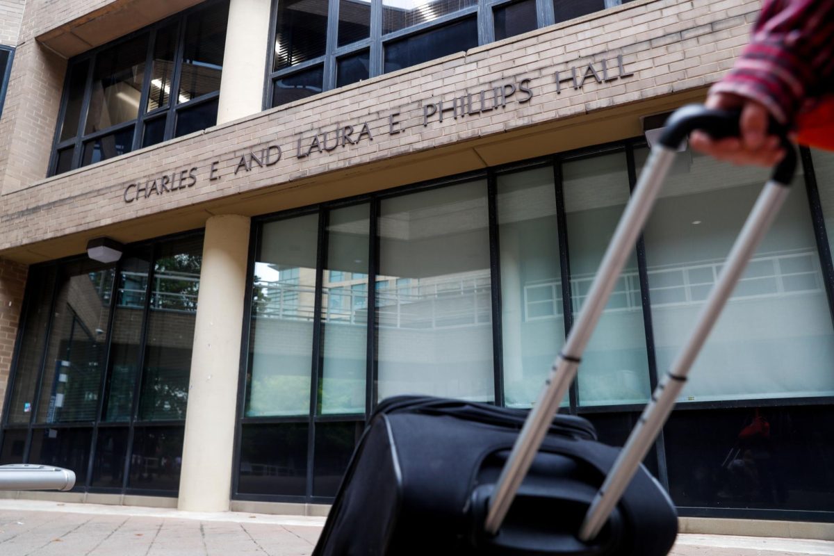 A person walks past Phillips Hall with a suitcase in 2023. 